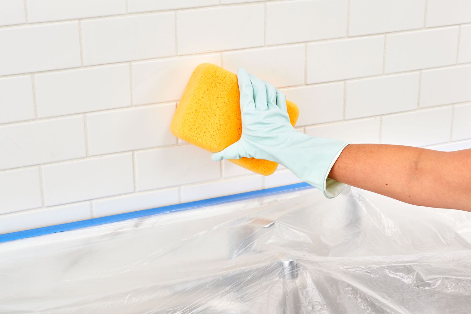 Wiping down the tile backsplash using a sponge.