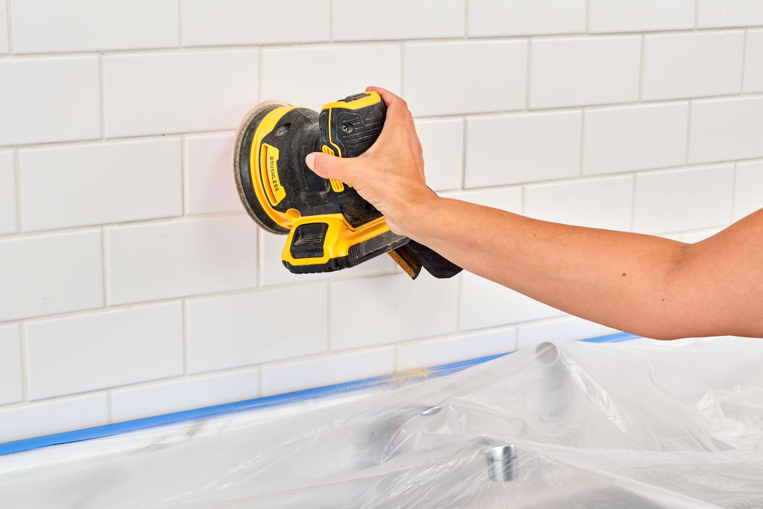 Using an orbital sander to smooth the surface of tiles.