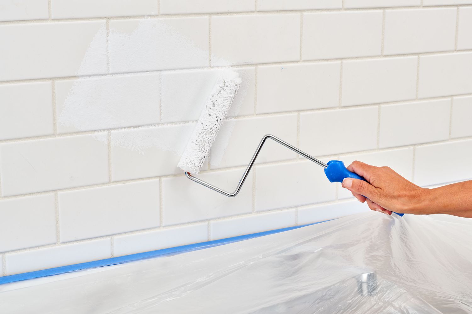 Using a roller to apply bonding primer to the backsplash.