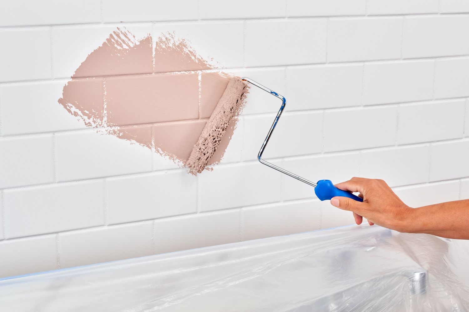 Using a roller to apply paint to a backsplash.