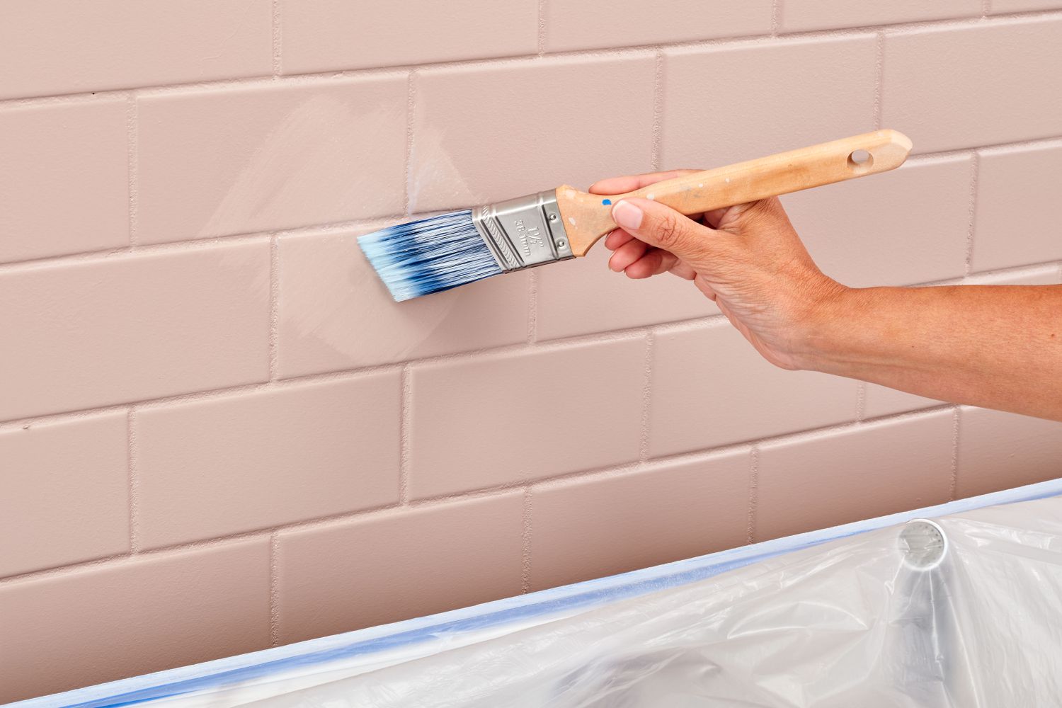 Using a paintbrush to apply a sealer to a backsplash.