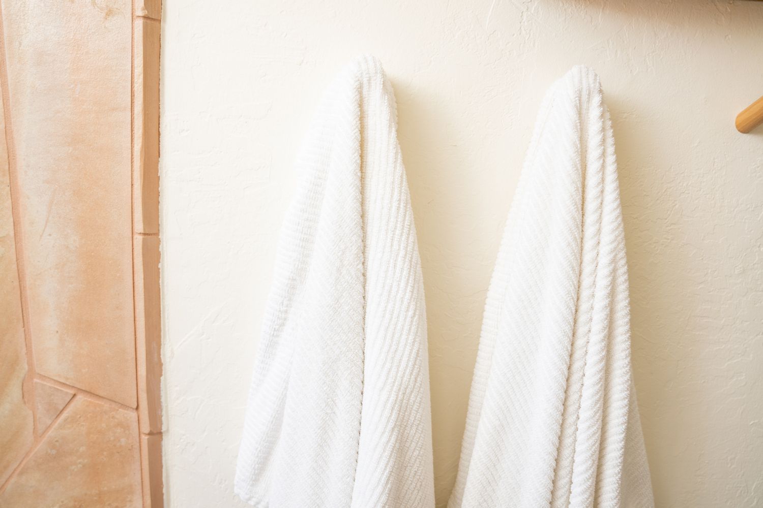 A white damp towel is draped over a wall stud in the bathroom.