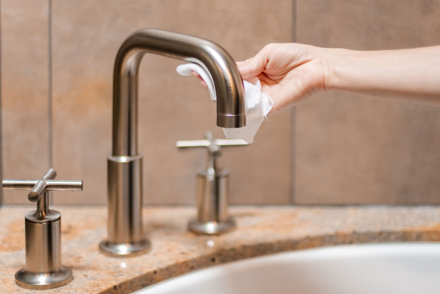 individual cleaning the bathroom sink hardware