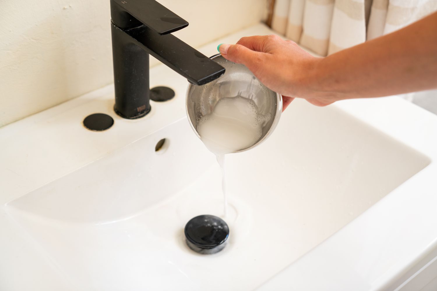 A mixture of baking soda and vinegar is poured into the sink drain to help eliminate the blockage.