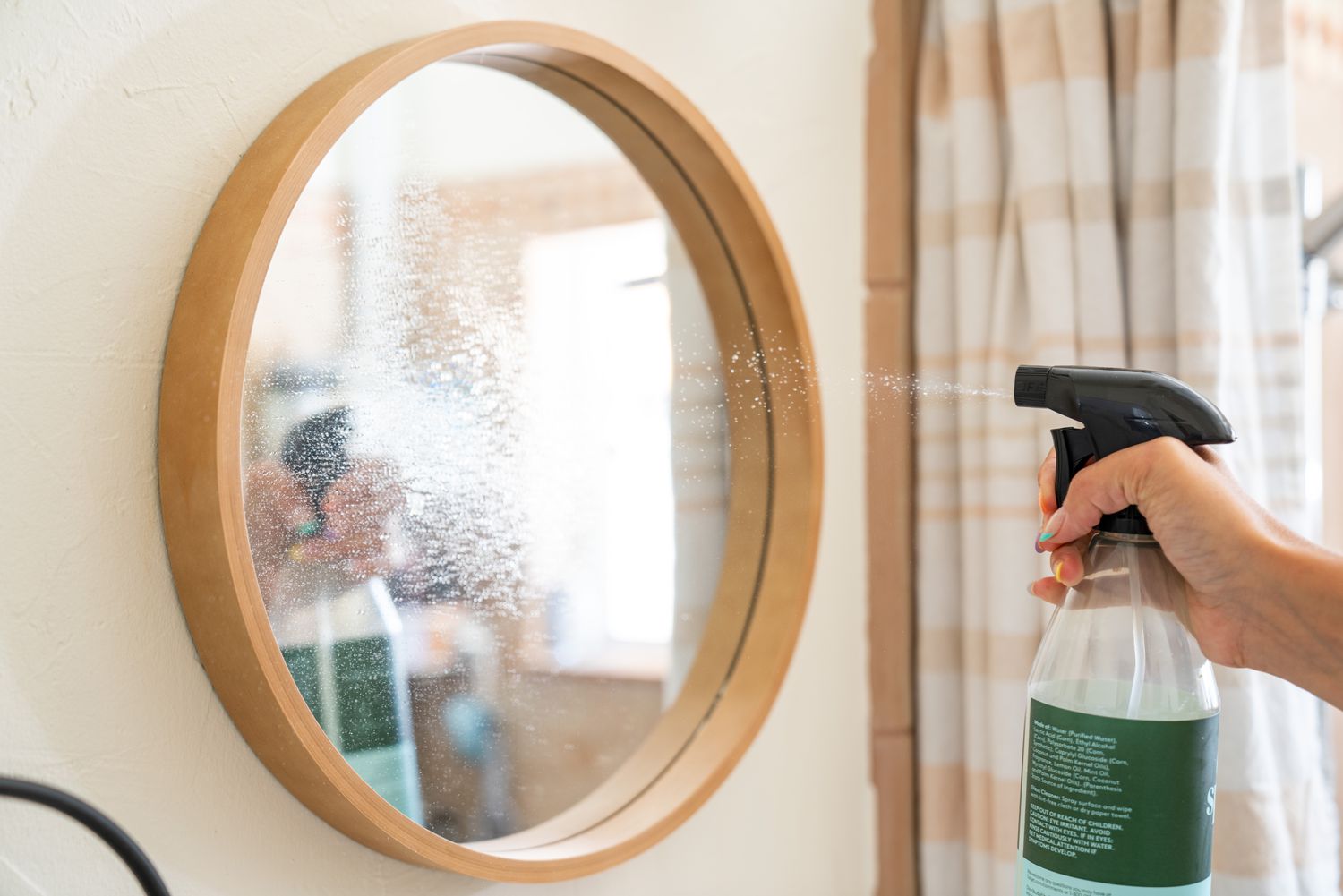 A commercial glass cleaner is applied to the mirror for its weekly maintenance.