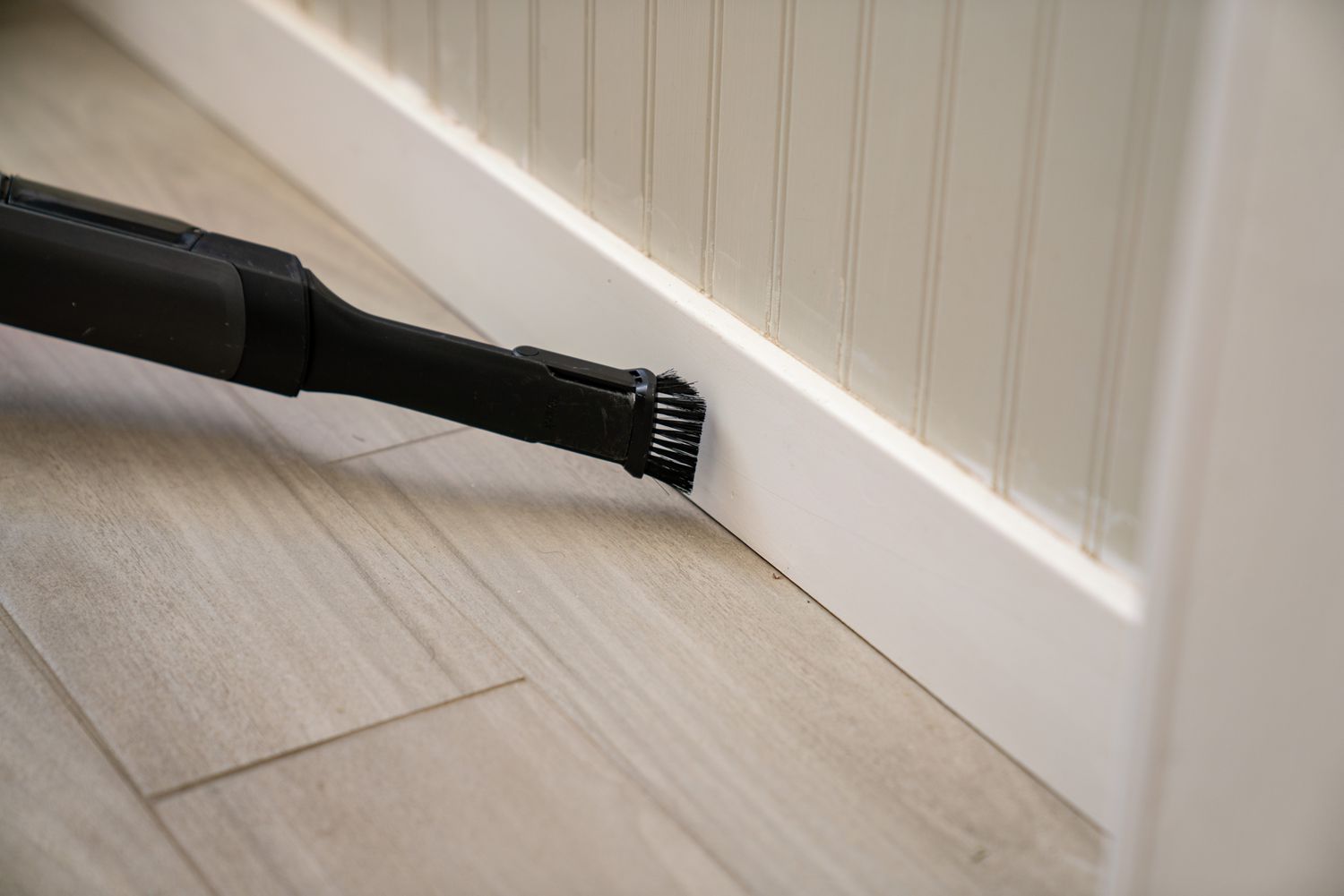 The baseboard in the bathroom was cleaned using a vacuum hose along with a brush attachment.