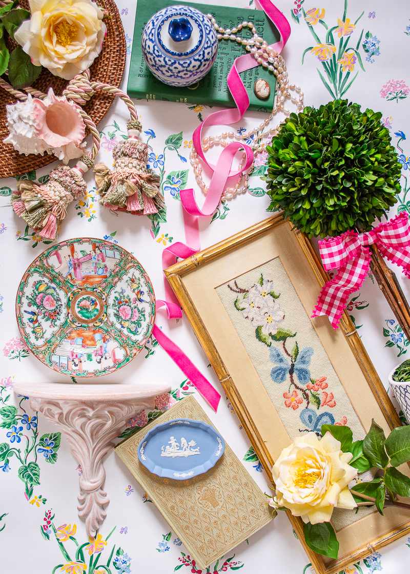 Art and ceramics featuring floral designs displayed on a tablecloth adorned with a floral pattern.