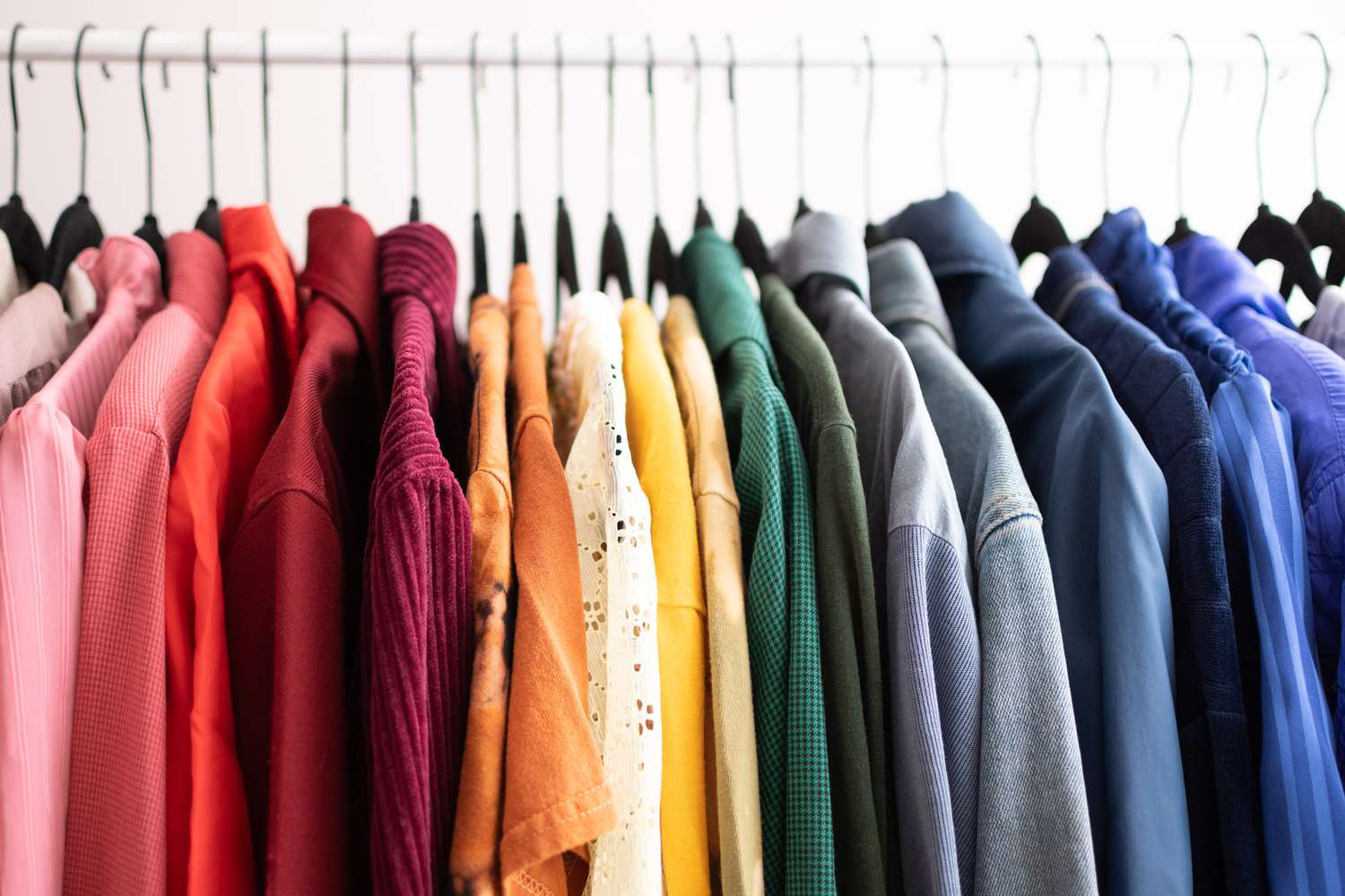 Garments arranged on hangers and sorted by color.