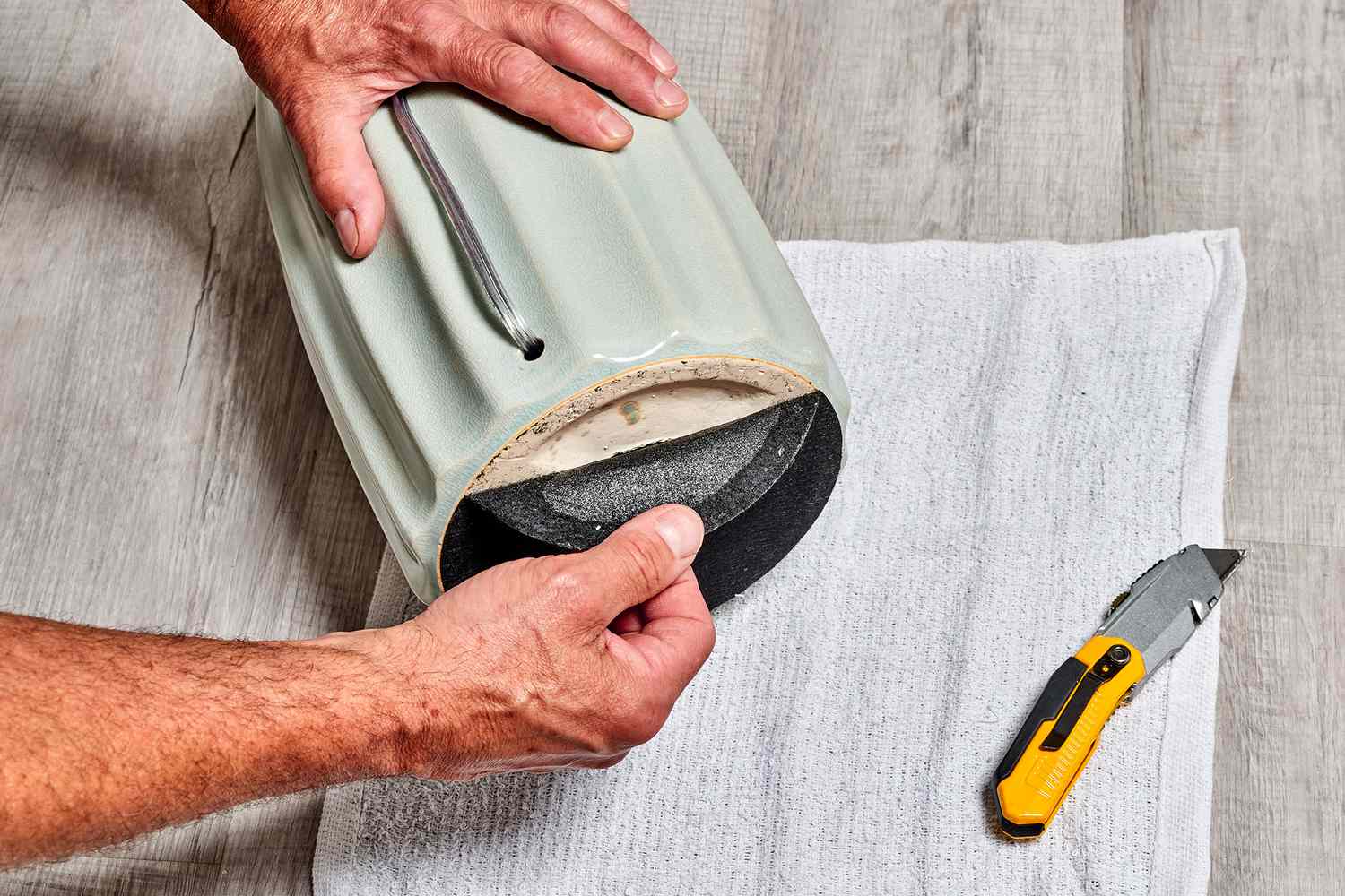 The felt-lined base was removed from the bottom of the lamp, positioned beside a yellow utility knife and a towel.