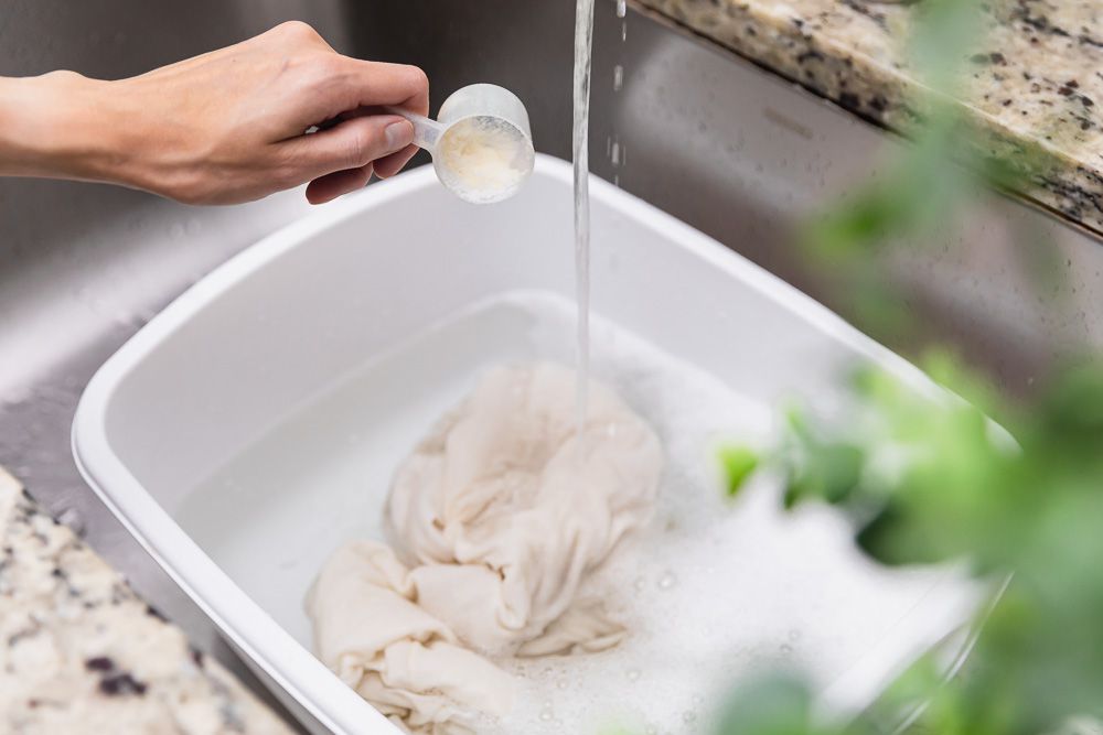 A white bucket filled with cherry-stained fabric has oxygen bleach applied to it.