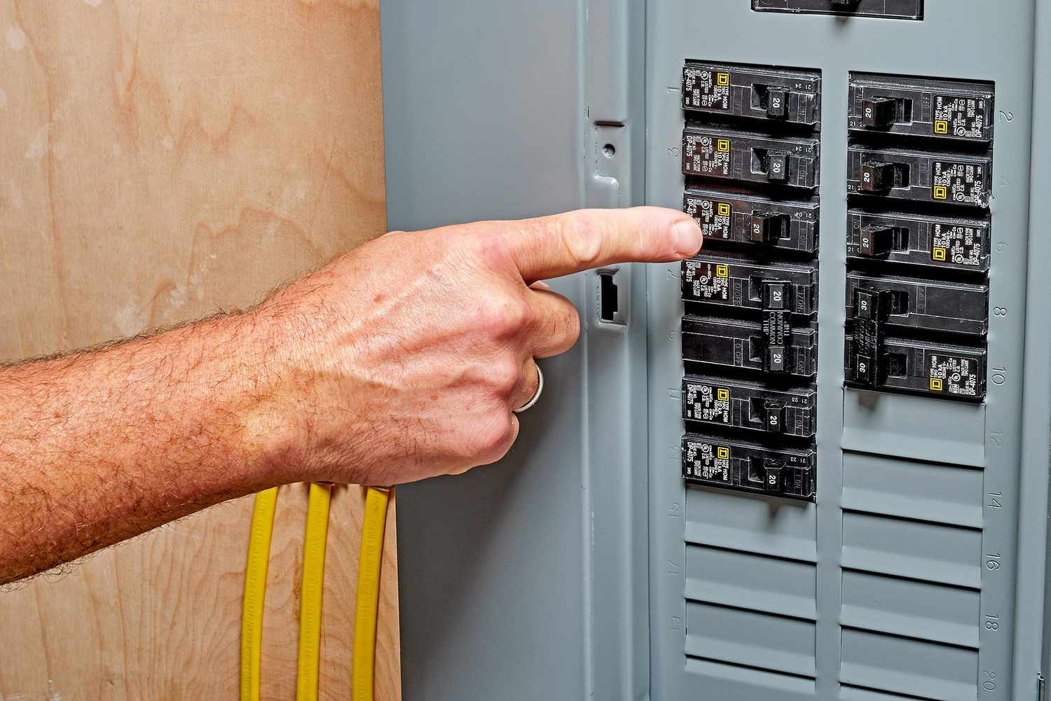 A finger indicating the tripped circuit breaker within the service panel.