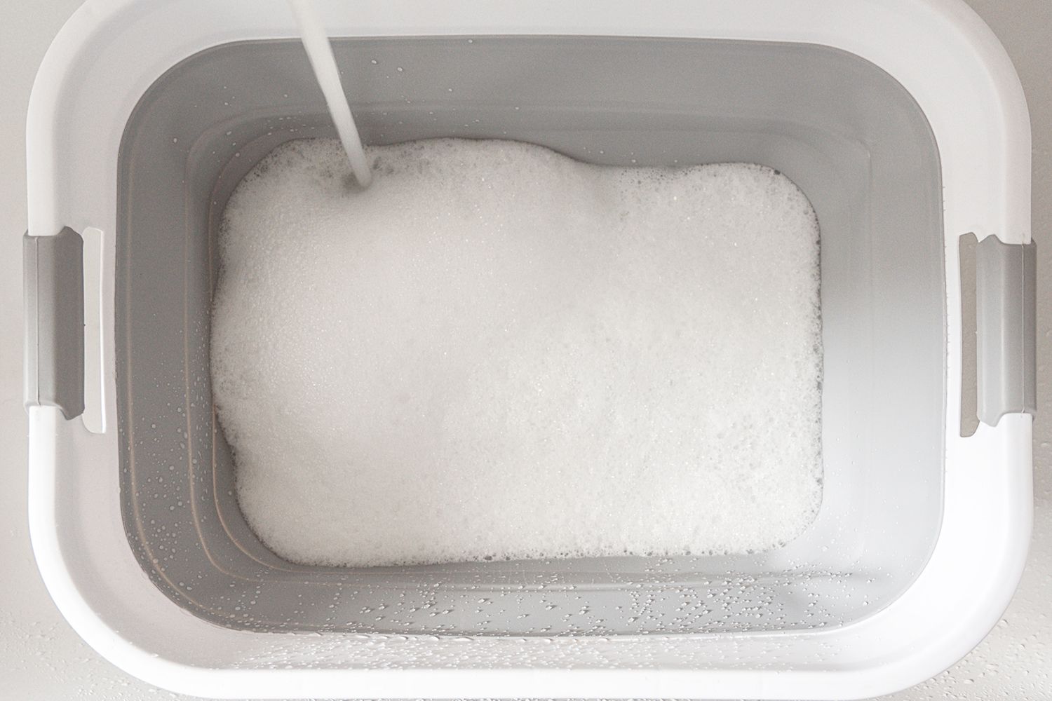 A white plastic container filled with water and a mild, high-performance detergent.