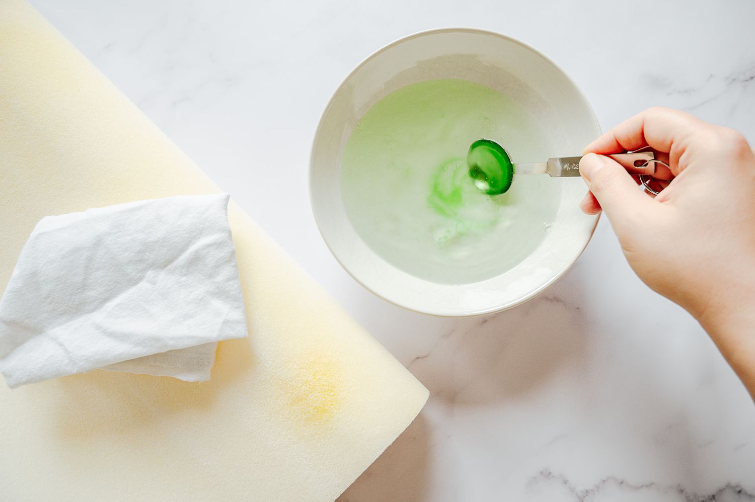 A small bowl filled with water and green dish soap can be used for spot cleaning pillows.