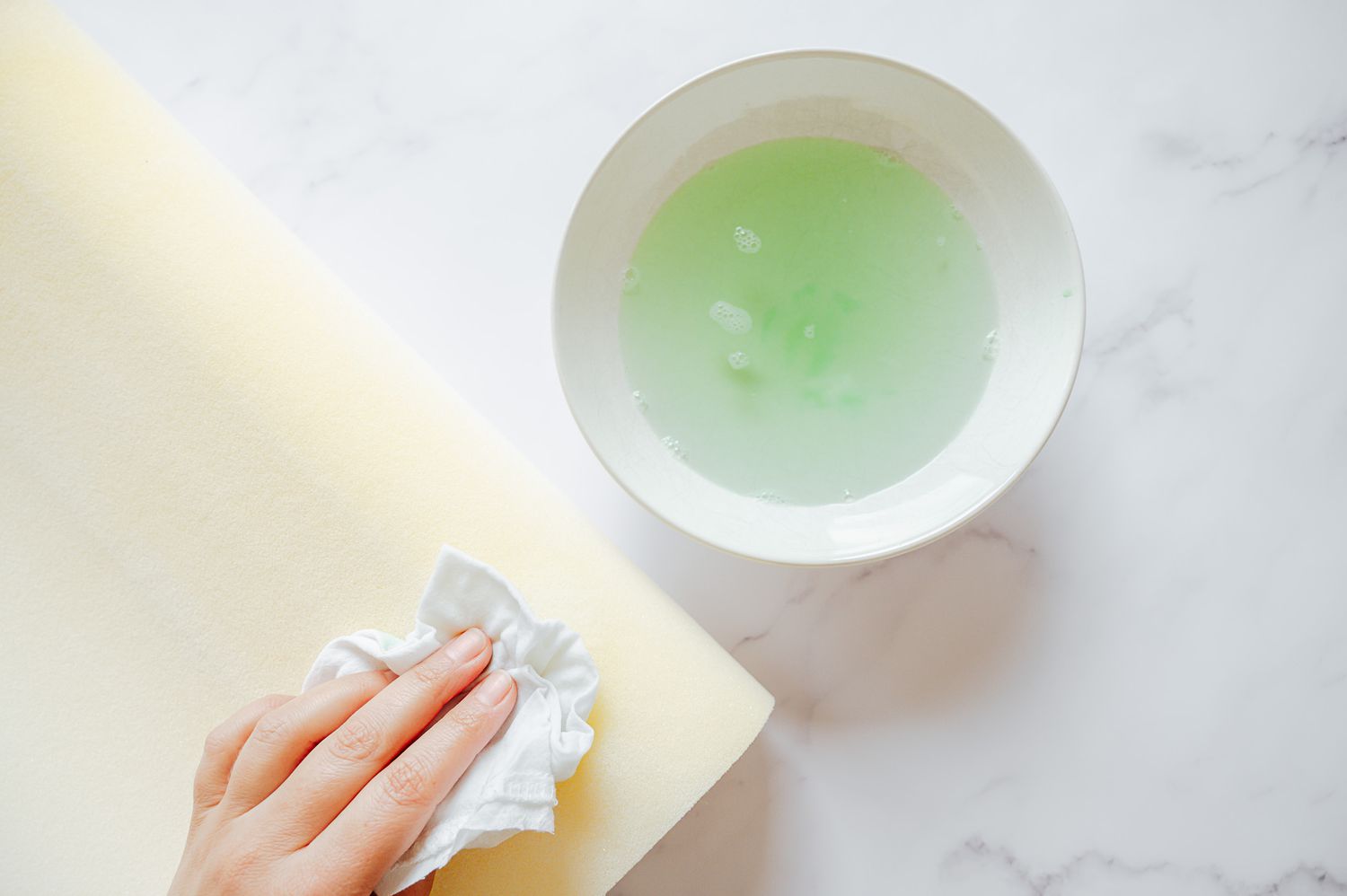 A memory foam pillow was treated for stains using a white cloth and a blotting solution.