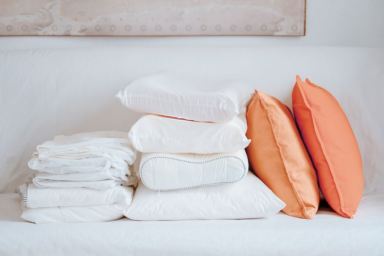 Latex and memory foam pillows and bedding arranged in a folded and stacked manner.